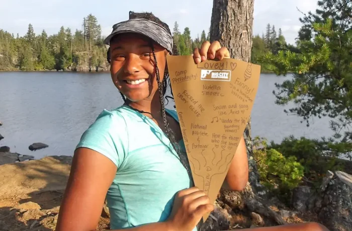 lovey.webp Lovey facing the camera while holding a Big City Mountaineers flag covered with handwritten signatures.